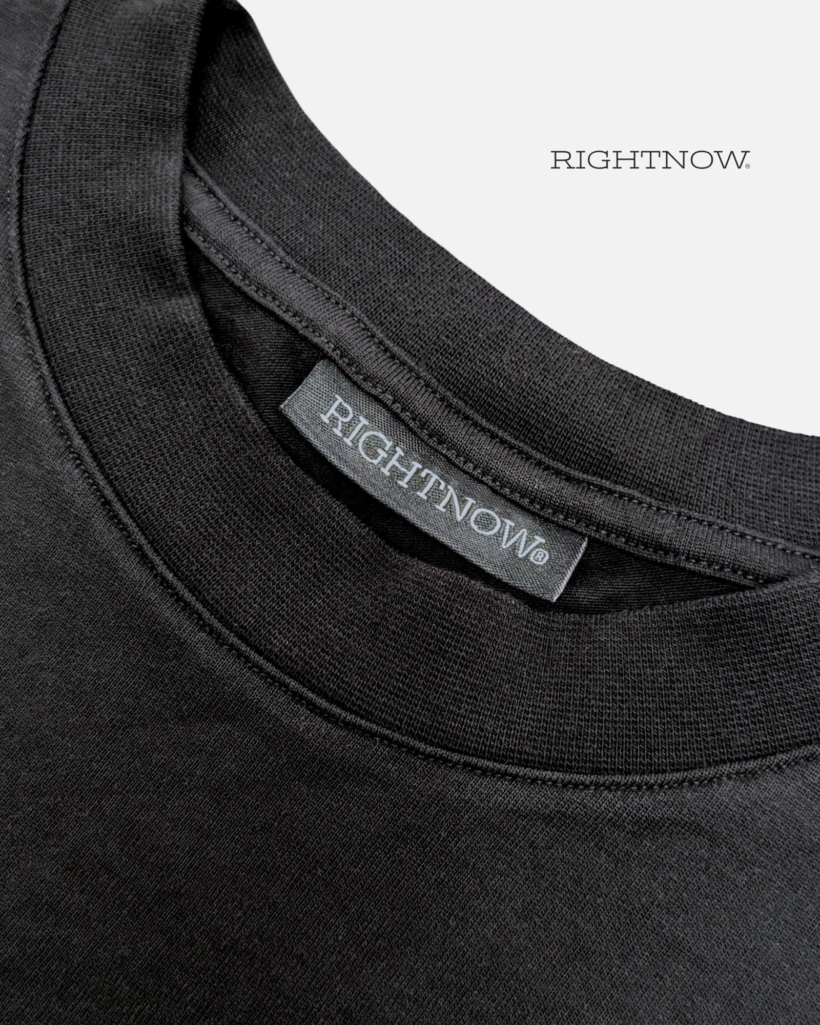 Brand logo label sewn on the back of the collar of a matt black Moment cotton oversized t-shirt.