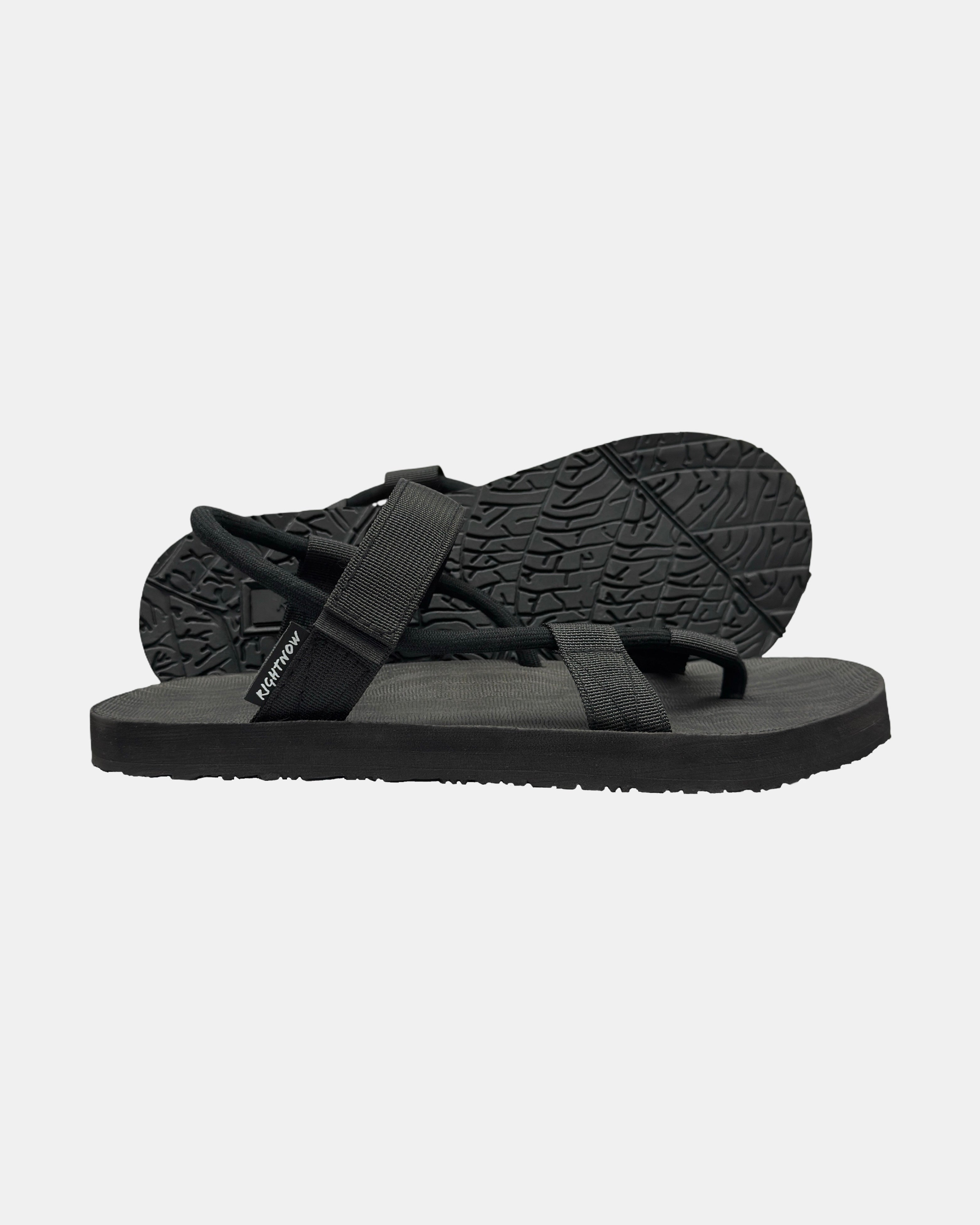 Men's elegant-tone minimalist sandal with flexible strap and an open-toe design, with the black rubber textured anti-slip sole behind it.