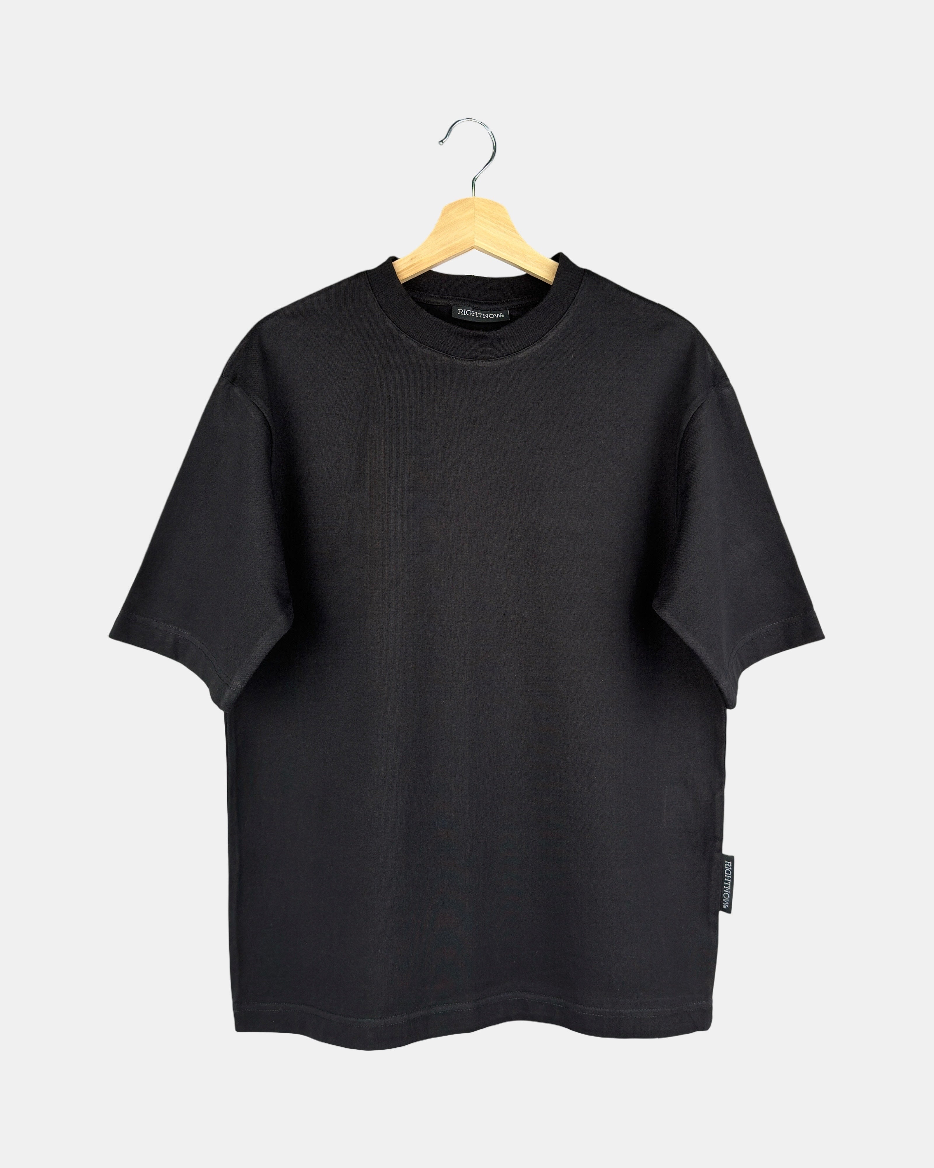 Unisex Moment oversized plain t-shirt in matt black, made from premium cotton, shown from the front to feature its butterfly-knitted crewneck collar on a hanger.