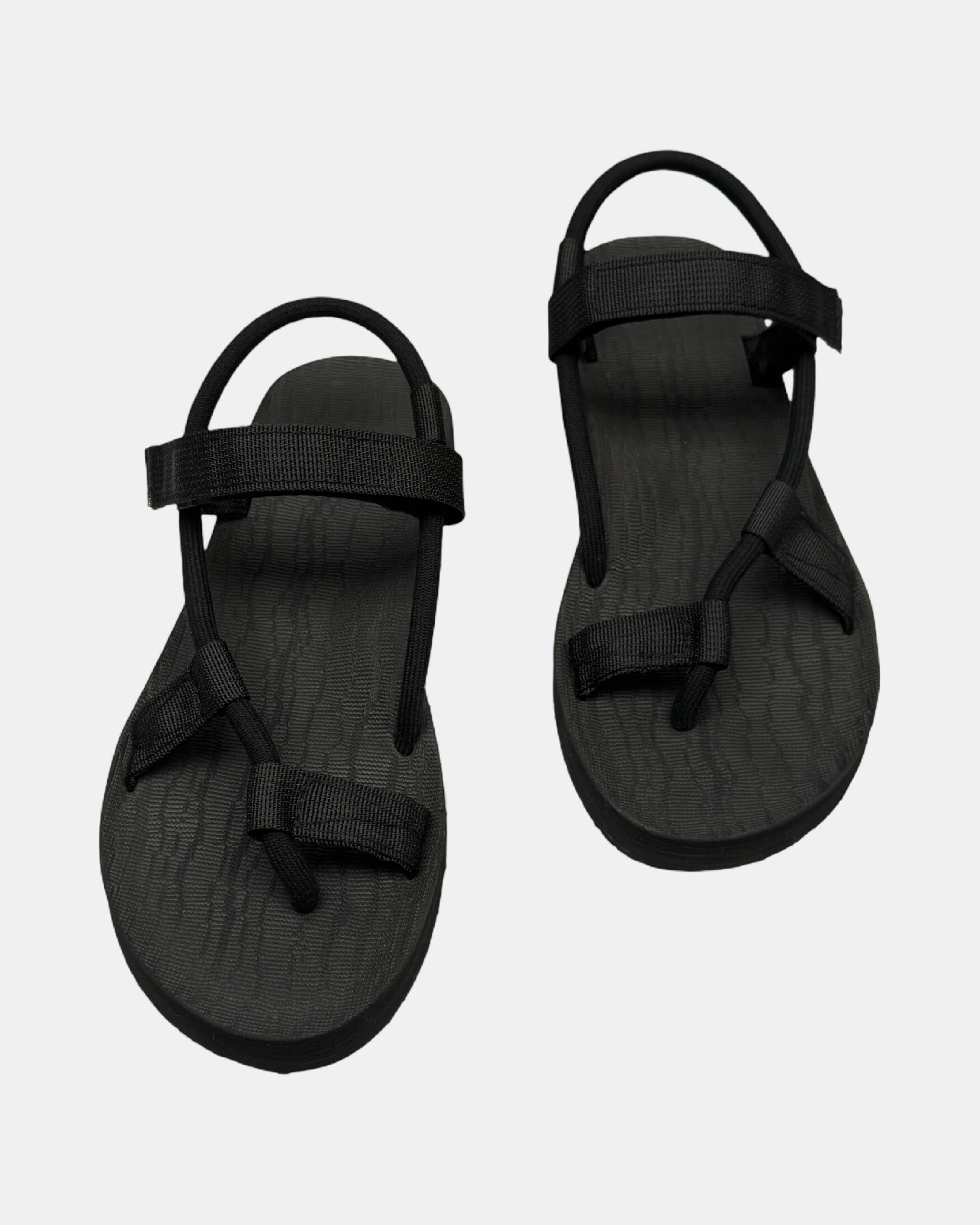 Front view of a pair of matt black rubber women’s roman sandal with open-toe design and adjustable ankle strap.