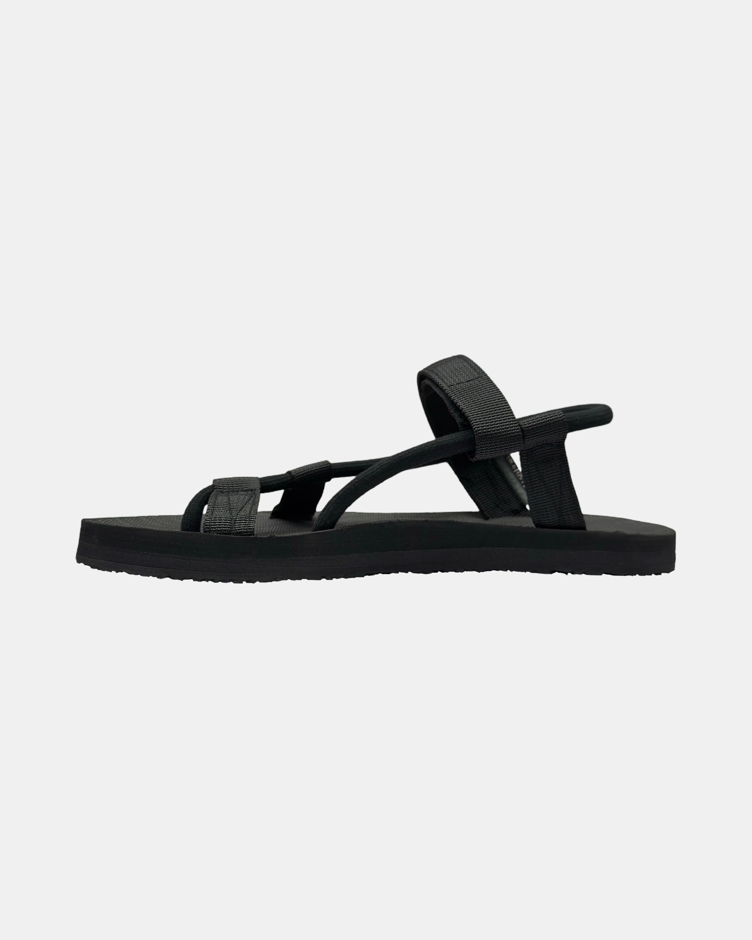 Women's matt black rubber Roman-style sandal seen from the left side, highlighting the contoured and grooved topsole with embedded arch support.
