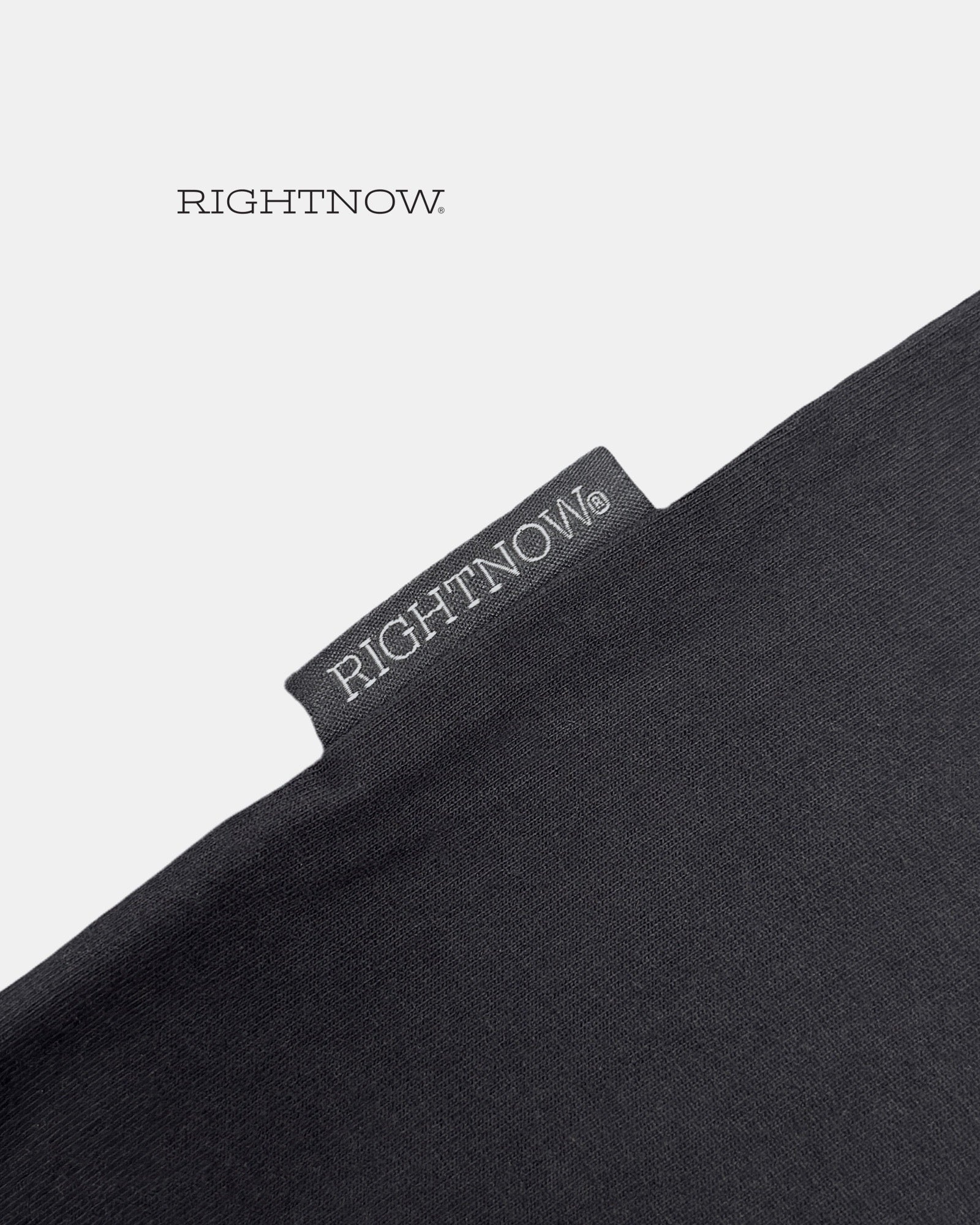 Brand logo label sewn on the outside of a matt black Moment cotton oversized plain t-shirt.