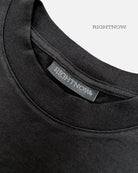 Brand logo label sewn on the back of the collar of a matt black Moment cotton oversized t-shirt.