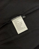 Care and composition label sewn into the side seam of a matt black Moment cotton oversized t-shirt.