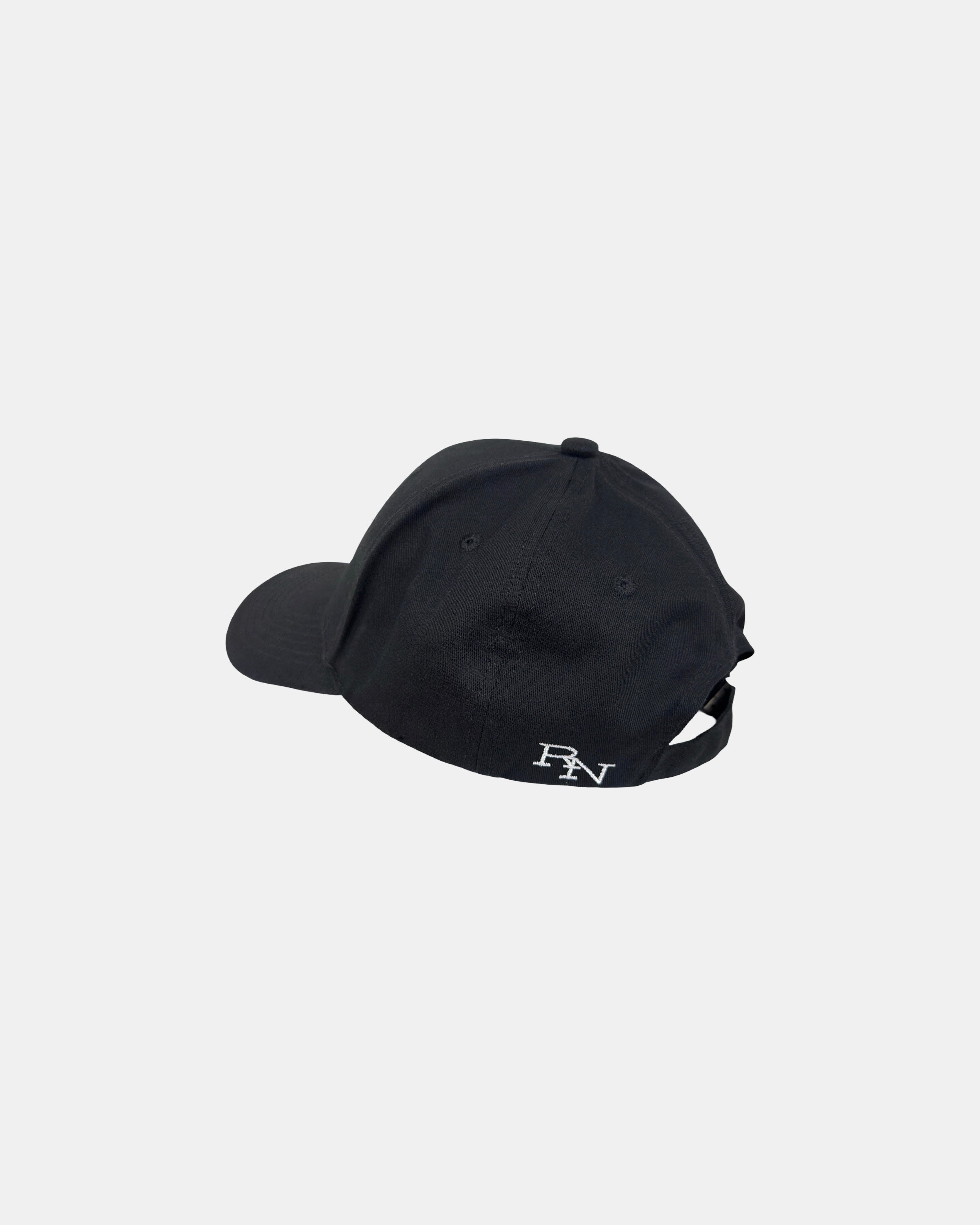 Angled 45-degree back-left view of a matt black Ignite cap, featuring the full 'RN' brand logo embroidery, quietly inspiring everyone to be present.