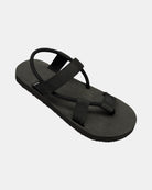 A 45-degree angled view of a men's matt black rubber Roman-style sandal with a single 360° flexible strap around the ankle.