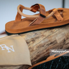 Brown EXPLOre roman sandal on a wooden log with RN branding visible.