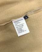 Care and composition label sewn into the side seam of a sand beige Moment cotton oversized t-shirt.