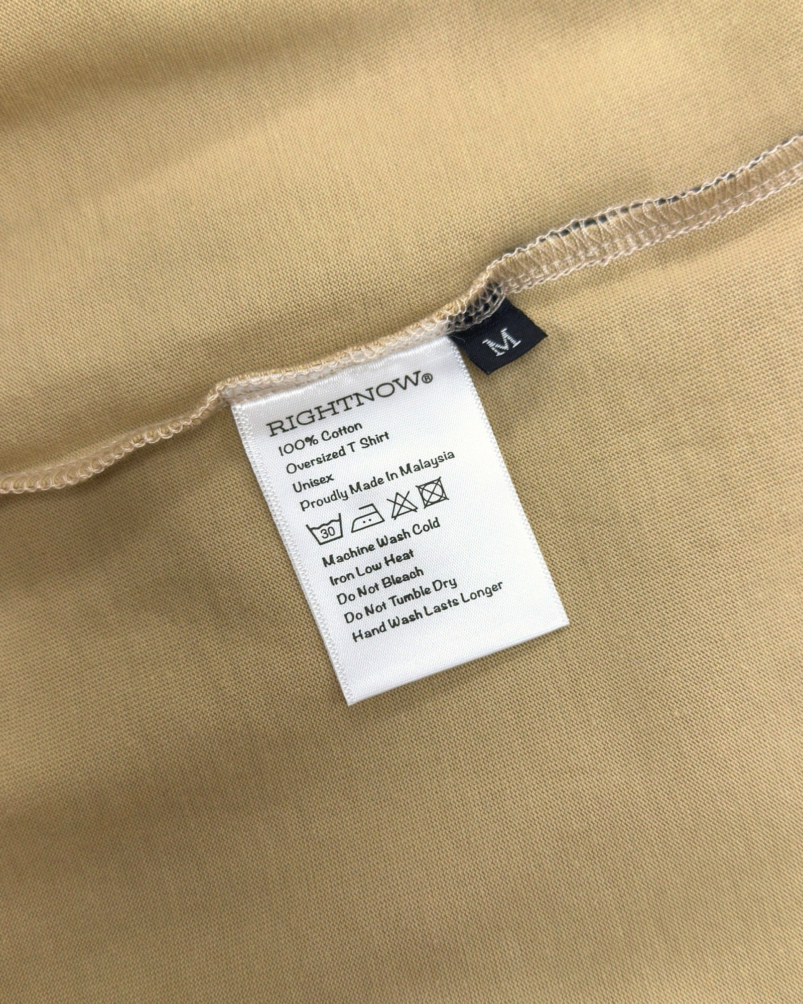 Care and composition label sewn into the side seam of a sand beige Moment cotton oversized t-shirt.
