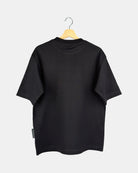 The back view of a unisex Moment oversized plain t-shirt in matt black, showing the clean design and drape of the premium cotton fabric on a hanger.