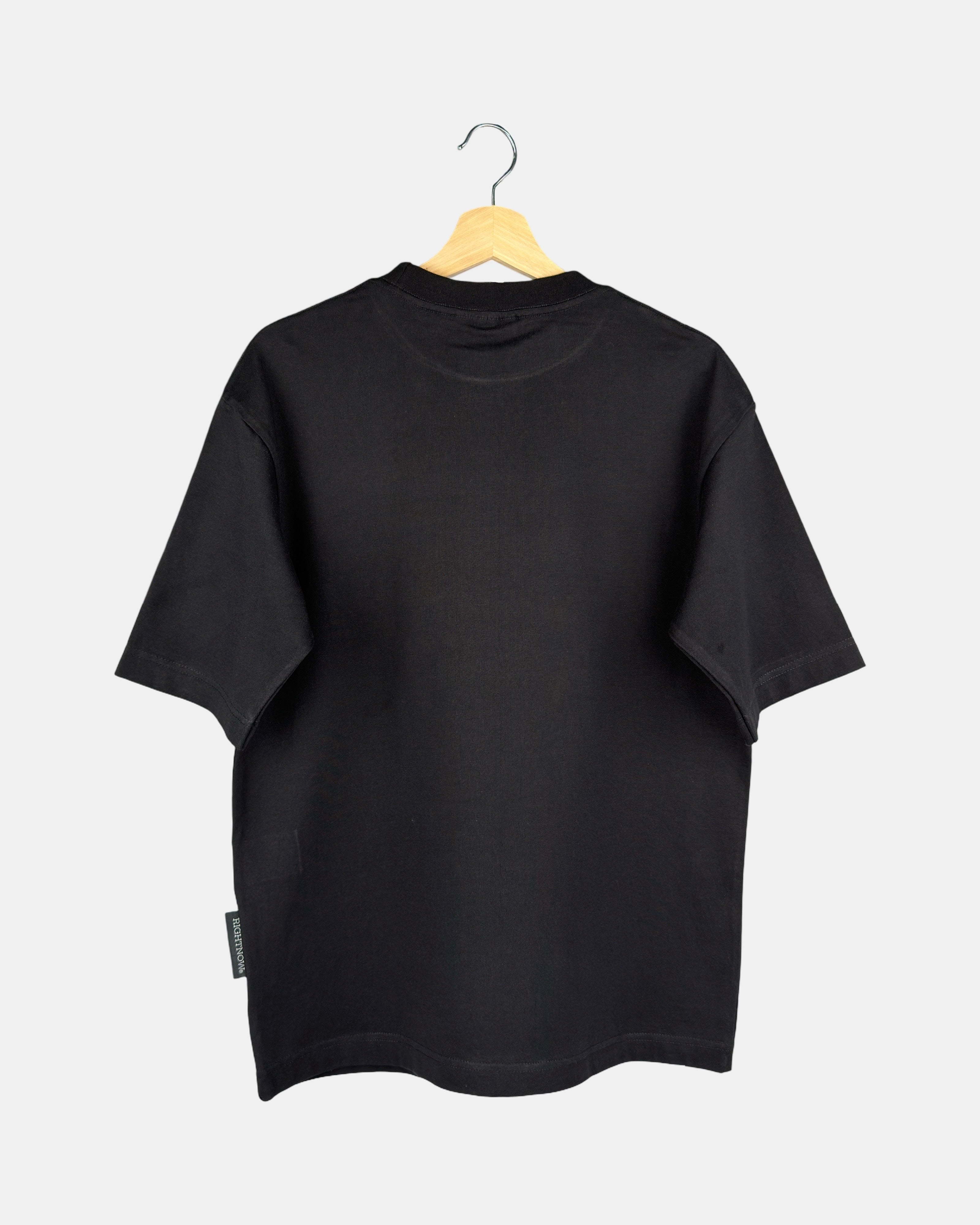 The back view of a unisex Moment oversized plain t-shirt in matt black, showing the clean design and drape of the premium cotton fabric on a hanger.