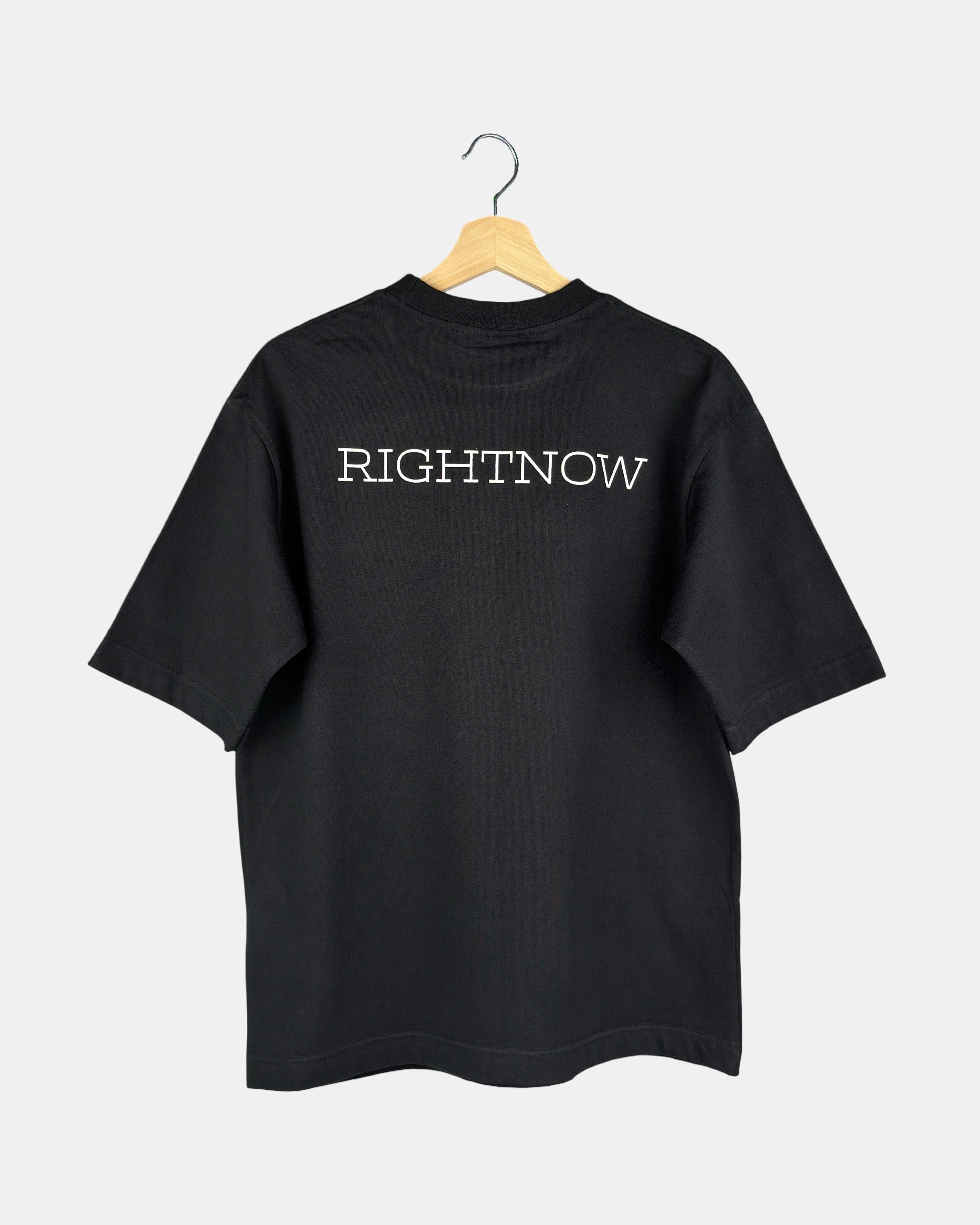 Back view of a unisex, matt black, cotton, oversized RIGHTNOW logo t-shirt with the brand name printed in large letters across the upper back.
