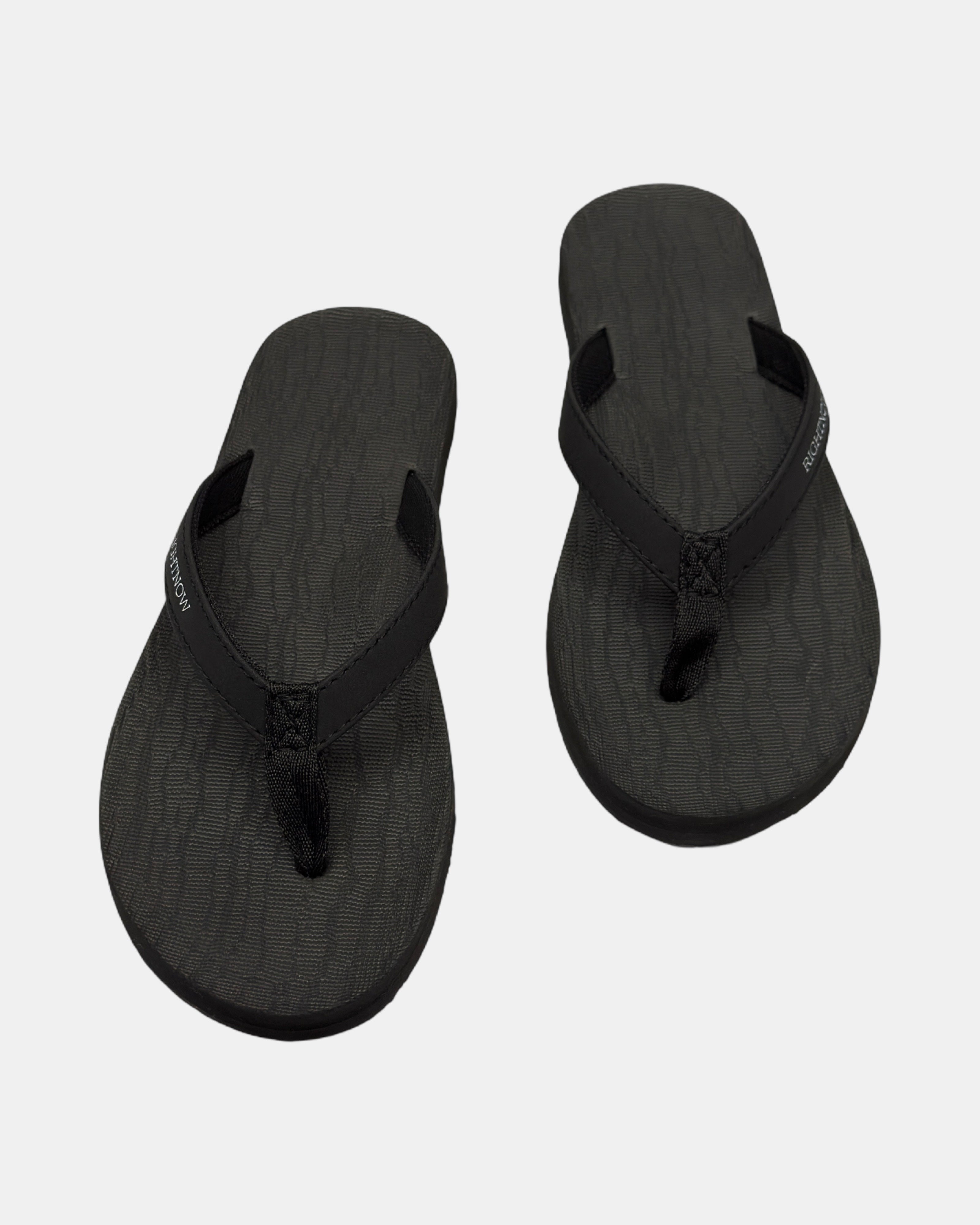 Front view of a pair of matt black rubber women’s thong sandal with open-toe design and textured footbed.