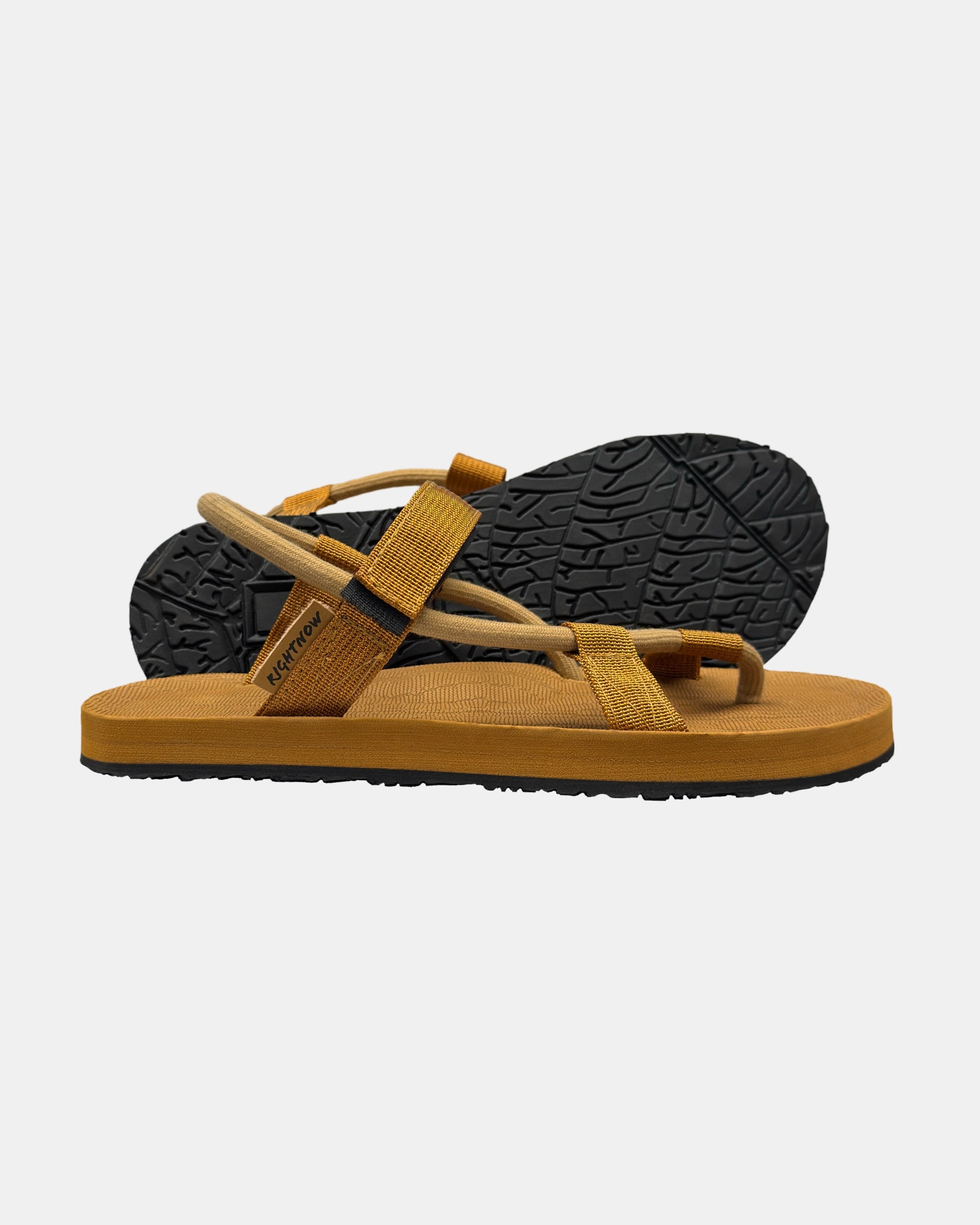 Women's earth-tone minimalist sandal with flexible strap and an open-toe design, with the black rubber textured anti-slip sole behind it.