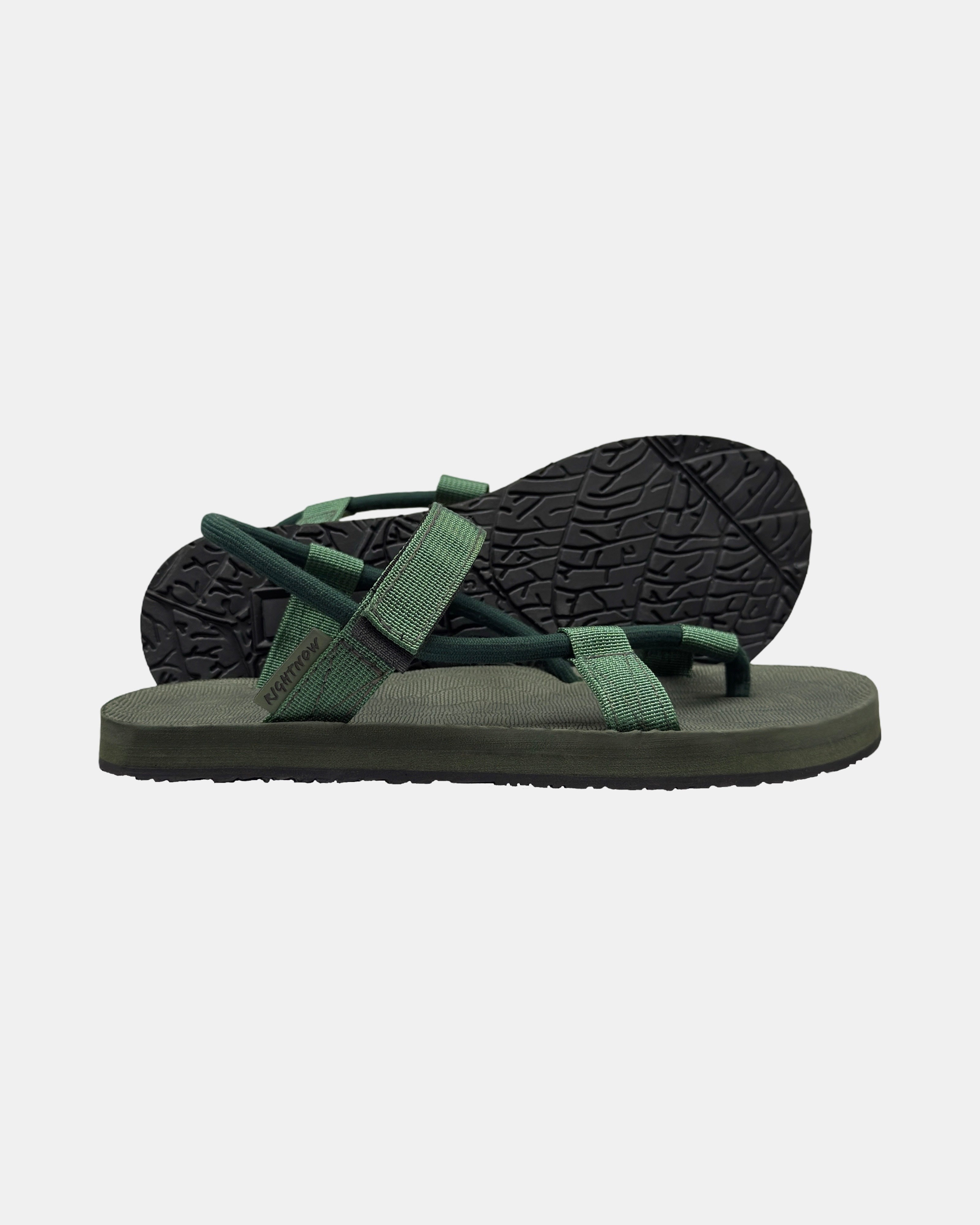 Women's forest-tone minimalist sandal with flexible strap and an open-toe design, with the black rubber textured anti-slip sole behind it.
